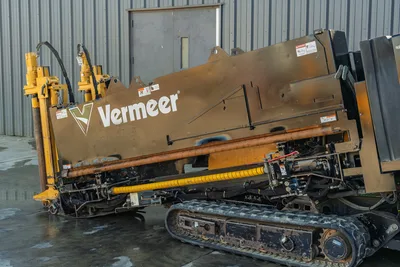 2021 Vermeer D23x30 S3 HDD rig side view showing drill frame, used drill pipe, rubber tracks, hydraulic components, and yellow vise jaw