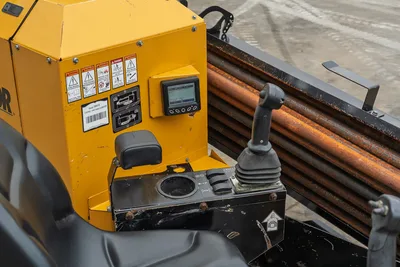 2018 Vermeer D8x12 operator control panel with LCD display, joystick, armrest, and loaded drill pipe rack visible behind