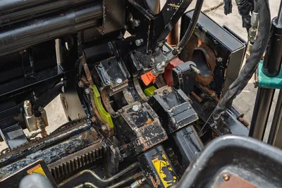 Close-up of 2018 Ditch Witch JT10 drill pipe vise assembly showing hydraulic cylinder, rack gear, and linkages in condition.