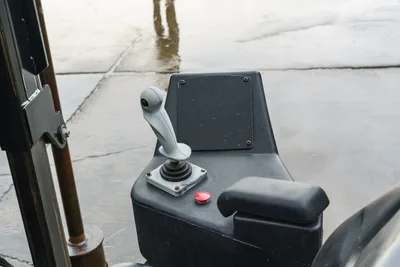 2015 Ditch Witch JT20 operator control console showing gray joystick, red emergency stop button, and armrest closeup