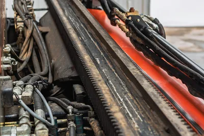 Close-up of rack-and-pinion drill carriage on 2018 Ditch Witch JT20, highlighting hydraulic hoses and steel rail condition.