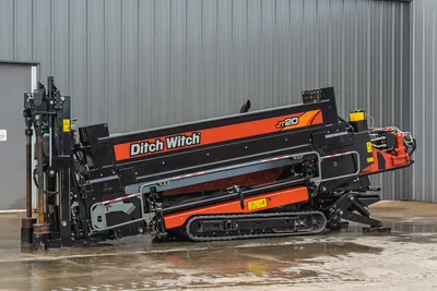 Ditch Witch JT20 HDD rig with orange/black frame, tracked undercarriage, drill head, operator cab, engine compartment, and drill pipe storage—side view