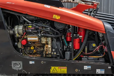 2018 Ditch Witch JT10 open engine compartment showing diesel engine, red Baldwin filters, hydraulic lines, and battery