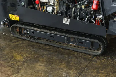 2015 Ditch Witch JT20 rubber track and undercarriage close-up, hydraulic components, Baldwin filter, and danger decal visible above.