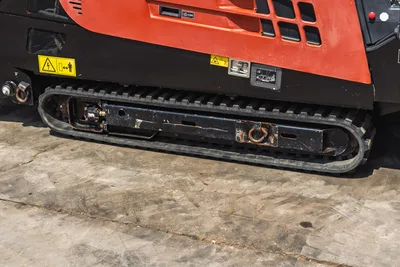 2021 Ditch Witch JT20 rubber track close-up, worn undercarriage with hydraulic drive motor, tie-down rings, safety decals visible