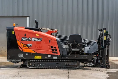 2018 Ditch Witch JT10 HDD drill, driver-side profile, orange hood, rubber tracks, loaded drill pipe rack, carriage assembly visible