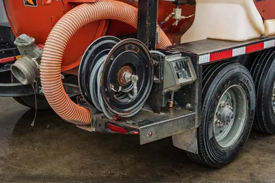 2021 Ditch Witch HX50 rear corner showing orange suction hose, hose reel, control box, tandem axle, and red mud tank.