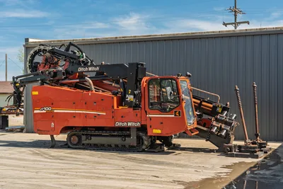 2014 Ditch Witch JT100 Mach 1 HDD drill, driver-side view, enclosed cab, rubber tracks, drill pipe loaded, anchors deployed