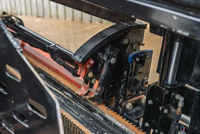 Ditch Witch JT20 rotary head and drill pipe assembly with red clamp and hydraulic cylinders, side close-up view showing worn operational condition