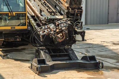 2017 Vermeer D100x140 S3 drill carriage and spindle close-up showing rack-and-pinion thrust frame, anchor plate, hydraulic lines, wear from use.