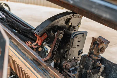2017 Ditch Witch JT20 carriage assembly close-up showing rack gear, vise clamp, hydraulic hoses, and wear-worn spindle components