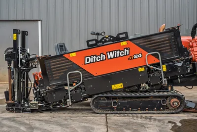 2024 Ditch Witch JT24 HDD drill, driver-side view, rubber tracks, angled drill frame, hydraulic manifolds, operator seat visible