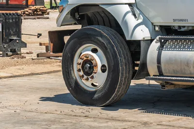 2015 International 7400 mud truck front steer tire, Hankook highway tread, steel wheel with surface rust, DOT356001 placard visible