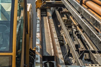 2017 Vermeer D100x140 S3 drill frame close-up showing rack-and-pinion thrust system, carriage rails, pipe rack with 3.5" drill pipe