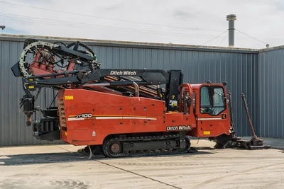 2014 Ditch Witch JT100 Mach 1 HDD rig, full profile view, rubber tracks, enclosed cab, loaded drill pipe rack, pipe carousel, anchor system deployed