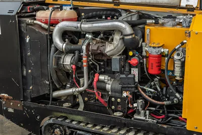2018 Vermeer D8x12 engine compartment open, showing diesel engine, exhaust piping, alternator, hydraulic filters, and rubber track