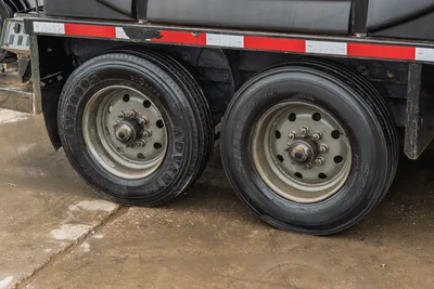 2023 Ditch Witch HX75 mud mixer trailer dual axle closeup, tandem tires with steel wheels, red reflective tape on frame