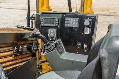 Vermeer D20x22 S3 operator console with LCD display, joystick controls, toggle switches, operator seat, and loaded drill pipe rack visible