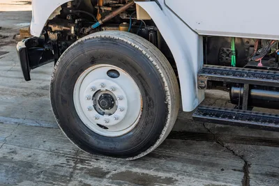 Passenger side close-up of 2000 Freightliner FL80 mud truck showcasing front axle, Toyo M170 tire, and step assembly.