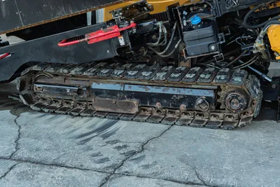 2019 Vermeer D40x55 S3 HDD steel track close-up, worn drive sprocket, hydraulic lines, red anchor visible overhead