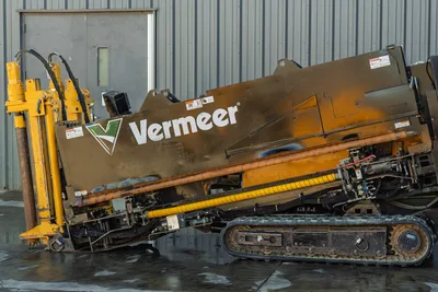 Vermeer D23x30 S3 HDD rig side view showing drill carriage, thrust frame, rubber tracks, hydraulic lines, and wear-marked enclosure panels.