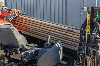 Ditch Witch JT10 HDD rig side view showing drill pipe carrier, orange rotary head, and 1.66" diameter drill pipe bundle