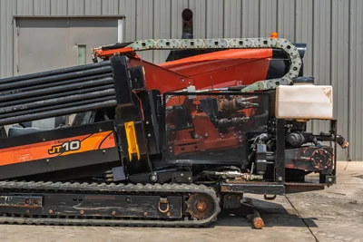 2018 Ditch Witch JT10 HDD drill, side profile showing rack with drill pipe, rubber tracks, and exposed engine compartment.