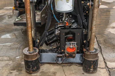 Front view of 2018 Ditch Witch JT20 drill frame, stabilizer legs, hydraulic hoses, and pipe breakout clamp mechanism.