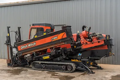 2016 Ditch Witch JT25 HDD drill, 3/4 left view, drill pipe loaded on carriage, enclosed cab, rubber tracks, anchor system visible