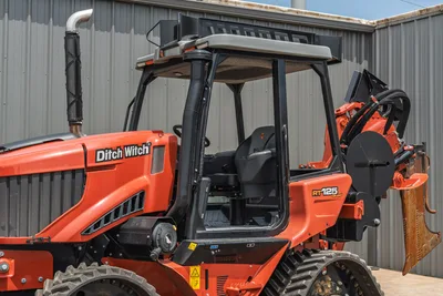 2024 Ditch Witch RT125Q cab interior view, operator seat, ROPS canopy, exhaust stack, RT125 Quad decal, trencher attachment visible