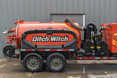 2023 Ditch Witch HX75 mud recycler, driver-side view, orange vacuum tank, dual-axle trailer, hose reel, vacuum pump, flexible intake hose