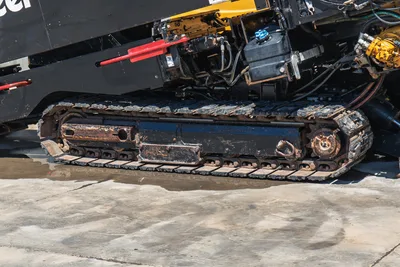 2020 Vermeer D24x40 S3 rubber track close-up showing drive sprocket, idler, hydraulic lines, and red sonde housing above frame