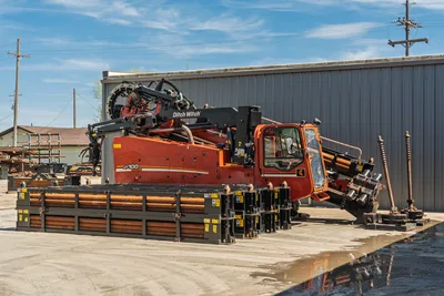 2014 Ditch Witch JT100 Mach 1 HDD rig, side view, enclosed cab, pipe rack with 3.5" drill pipe, vise assembly visible
