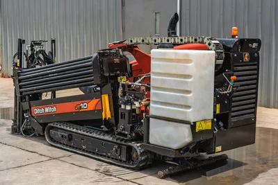 2018 Ditch Witch JT10 HDD rig, rear 3/4 view, rubber tracks, drill pipe rack loaded, fluid tank, engine compartment, amber beacon visible