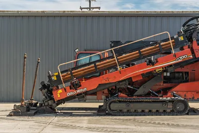 2014 Ditch Witch JT100 Mach 1 HDD drill, side view, loaded pipe rack, drill string attached, rubber tracks, wear visible
