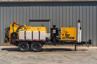 Vermeer LP873SDT trailer-mounted vacuum excavator, full side profile, yellow debris tank, dual-axle trailer, spoils separator, white poly tanks, suction hose