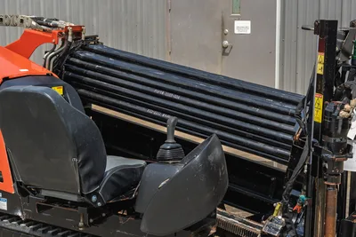 2018 Ditch Witch JT10 operator station, clean seat, joystick controls, and rack of drill pipe in profile view.