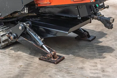 2017 Ditch Witch JT20 hydraulic anchor stake and stabilizer jack closeup, undercarriage frame, rubber track, fluid fittings visible