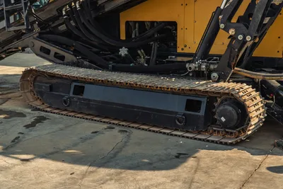 2017 Vermeer D100x140 S3 steel undercarriage track close-up, worn drive sprocket, hydraulic lines visible above
