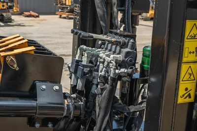 2023 Ditch Witch JT20 hydraulic valve block, bundled hoses, manual control lever, and safety decals viewed close-up