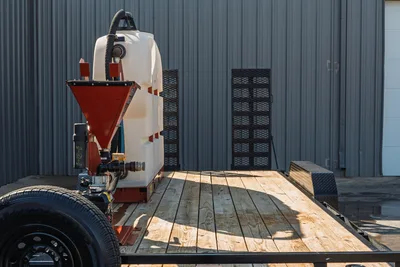 2023 MAXX-D C6X mud mixing trailer, side view showing white poly water tank, red bentonite hopper, pump valves, wood deck, mesh ramps