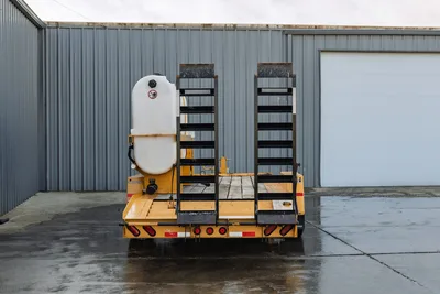 2021 TowMaster T-20D low-boy trailer, rear view, dual fold-down ramps, white poly water tank, yellow deck, red tail lights