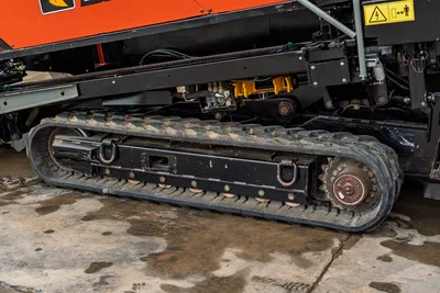 2021 Ditch Witch JT40 rubber track close-up, drive sprocket, undercarriage hydraulics, yellow fittings, electrical hazard decal visible
