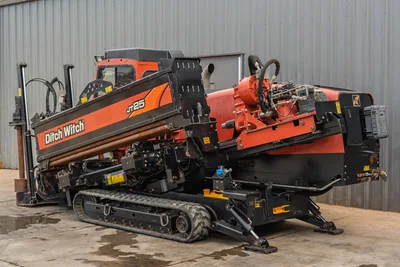 2016 Ditch Witch JT25 HDD drill, 3/4 rear angle, drill frame angled up, loaded drill pipe, carriage, spindle, rubber tracks visible