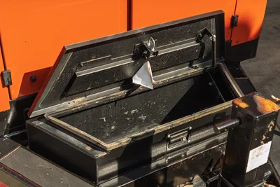 2022 Ditch Witch HX30 open black steel toolbox, lid raised, work-worn interior, mounted against orange machine body