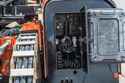 2021 Ditch Witch JT20 open utility panel with control switches, coiled cable, hydraulic fittings, and rubber tracks visible at left