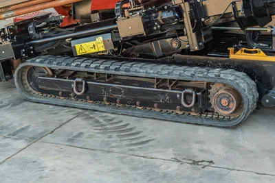 2021 Ditch Witch JT28 rubber track closeup showing drive sprocket, track frame, tie-down rings, and hydraulic components above