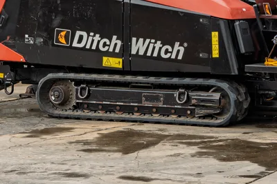 2021 Ditch Witch JT40 rubber track assembly close-up, showing drive sprocket, track pads, and black undercarriage with safety decals