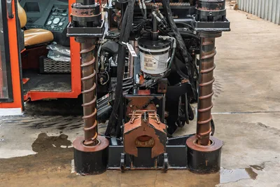 Rear view of 2012 Ditch Witch JT3020 drill rig, showing anchor stake cylinders with rack, carriage, and operator cab access.