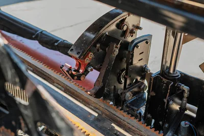 Ditch Witch JT20 drill pipe rack and clamp mechanism with hydraulic cylinder assembly, close-up view.